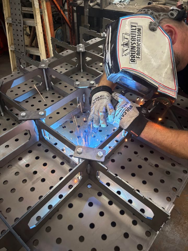 Fabricator tack welding a Datum fixture table rib matrix held by assembly draw plates